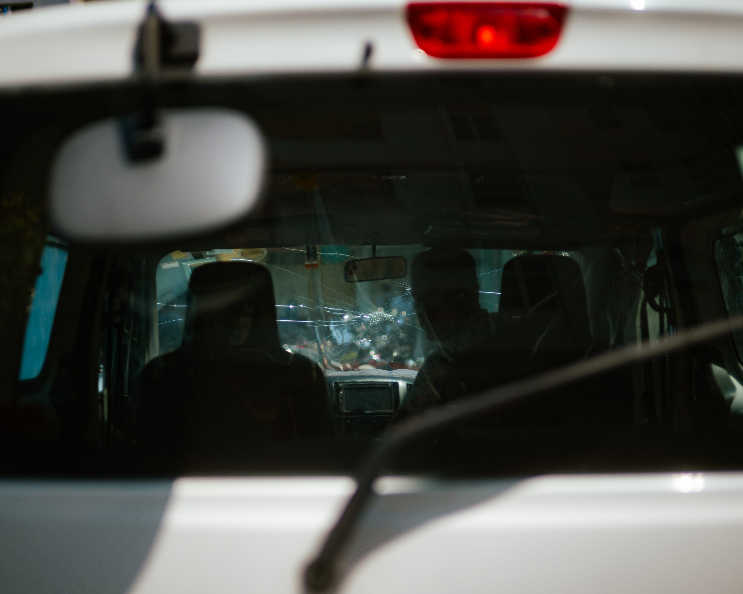 Two passengers seen through a cracked windshield in city traffic