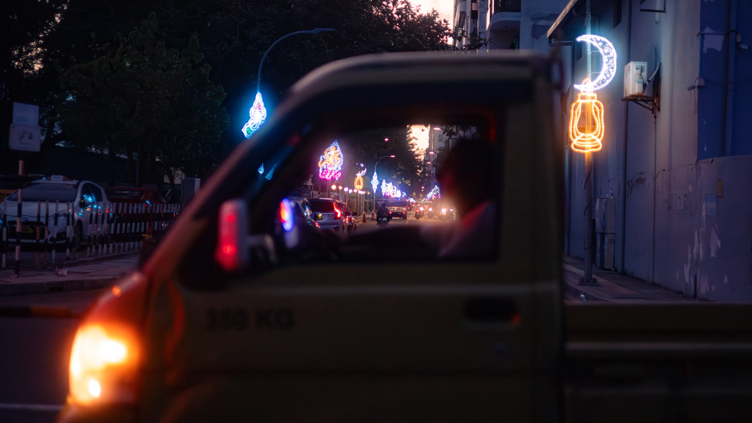 Ramadan neon lights lining a city street seen through a vehicle window at dusk