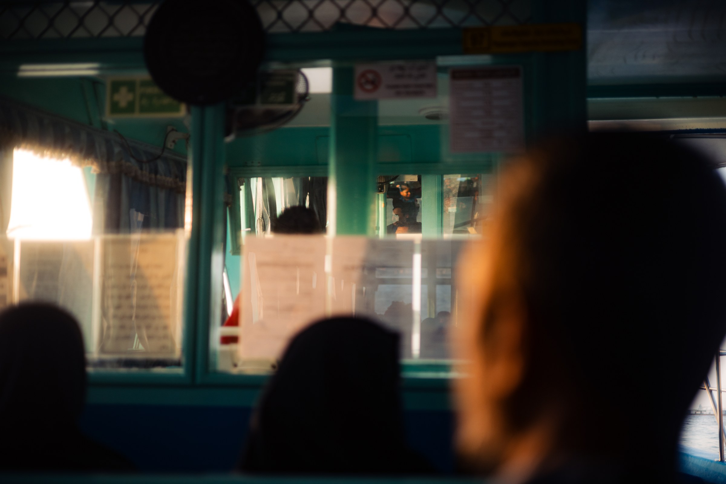 View through layered teal ferry cabin windows toward warm evening light